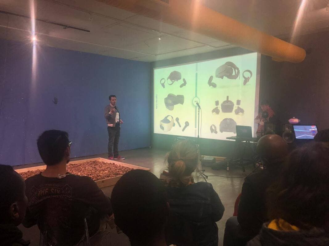 Speaker presenting a slide of VR headsets to a seated audience
